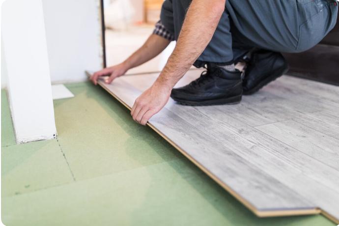 Worker installing laminated flooring boards during professional flooring installation