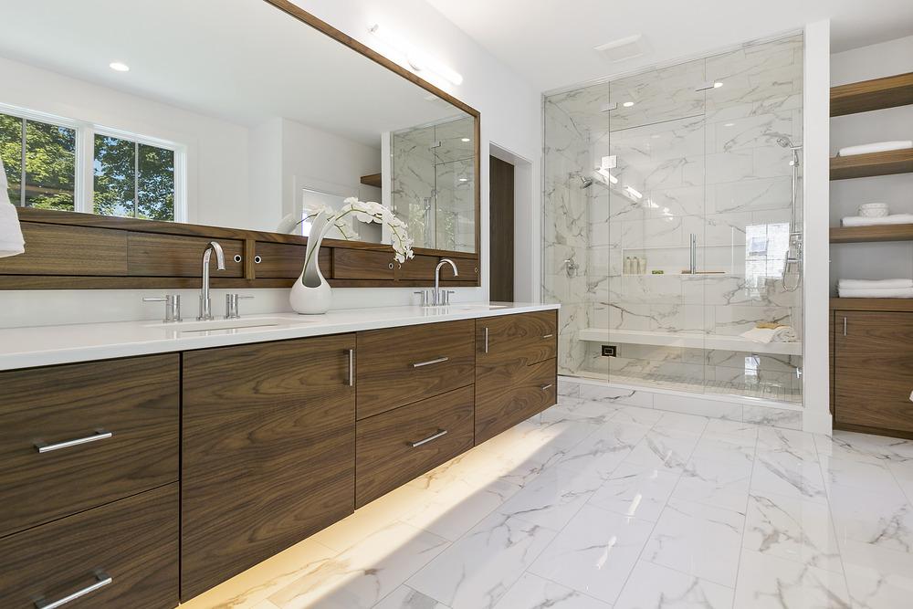 Modern spa-like bathroom with oversized vanity, walk-in glass shower, natural lighting, and upscale finishes.