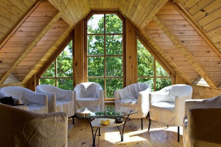 Finished attic sitting room in a Poconos home with a peaked ceiling and a full-height window wall