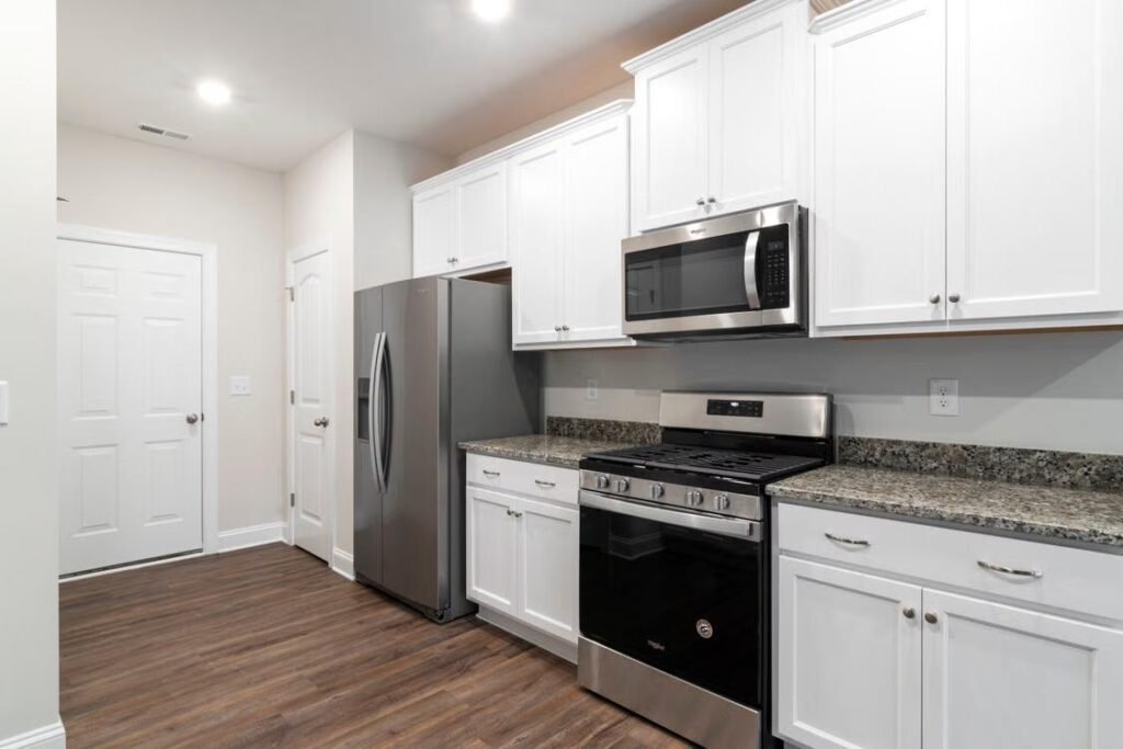 A kitchen with white cabinets and appliances